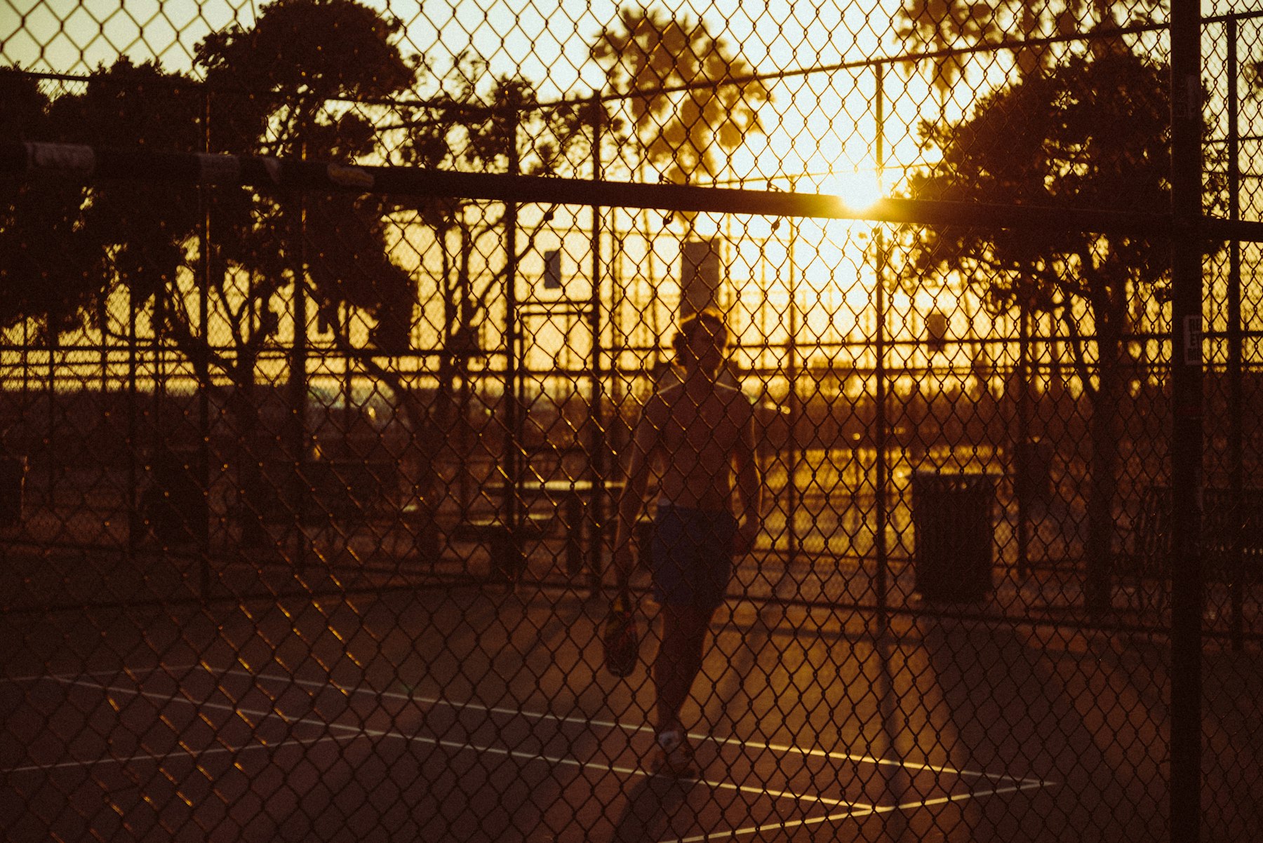 A player on a beachside court at sunset